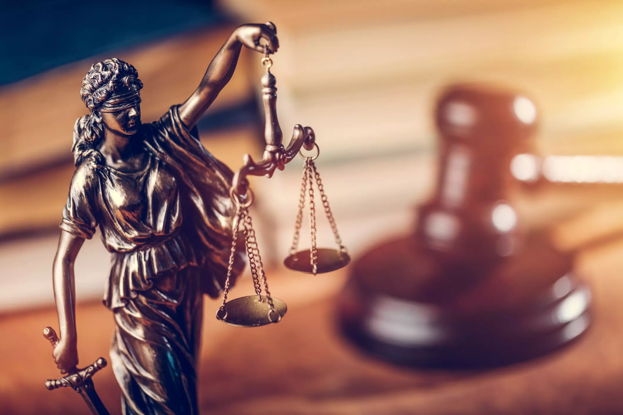 Lady of Justice and gavel with law books in the background.